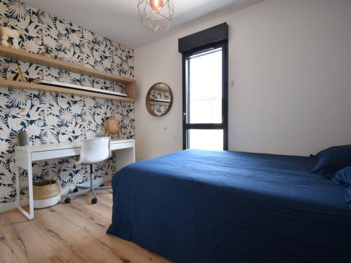 - une chambre avec un lit bleu et un bureau dans l'établissement Villa à Capbreton avec Piscine Chauffée, Proche Plages, Pistes Cyclables et Services Hôteliers Inclus - FR-1-791-7, à Capbreton