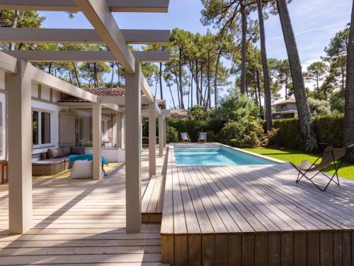 une arrière-cour avec une terrasse en bois et une piscine dans l'établissement Villa Rénovée à Hossegor avec Piscine Chauffée, Proche Golf et Plage - FR-1-791-15, à Soorts-Hossegor
