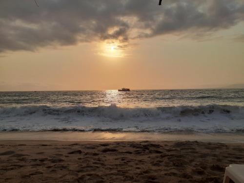 a boat in the ocean at sunset with the beach at Petit Bonheur - Calm Intimate - Terrace & Beach in Puerto Vallarta
