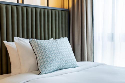 a bed with a blue pillow on top of it at Le Parchamp, a Tribute Portfolio Hotel, Paris Boulogne in Boulogne-Billancourt
