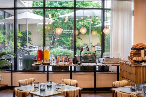 a restaurant with tables and a counter with food at Le Parchamp, a Tribute Portfolio Hotel, Paris Boulogne in Boulogne-Billancourt