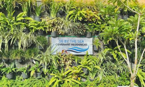 a sign on the side of a wall with plants at 50 By The Sea in Dehiwala