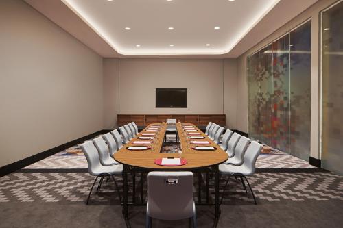 a conference room with a large wooden table and chairs at Aloft Langkawi Pantai Tengah in Pantai Cenang