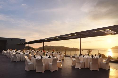 a group of tables and chairs on the roof of a building at Aloft Langkawi Pantai Tengah in Pantai Cenang