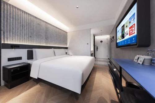 ein Schlafzimmer mit einem großen weißen Bett und einem Fernseher in der Unterkunft Atour Light Hotel Nanjing Museum in Nanjing