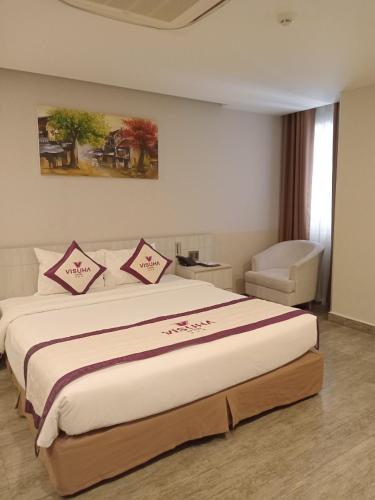 a bedroom with a large bed and a chair at VISUHA HOTEL in Ha Tien