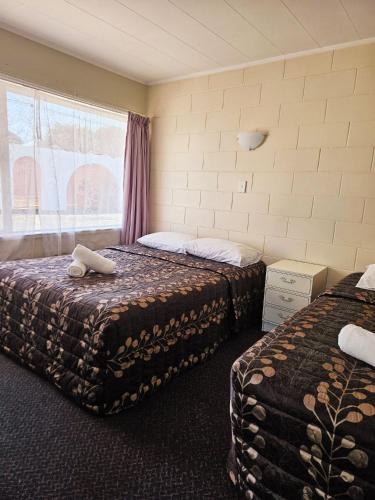 a hotel room with two beds and a window at Takanini Park Motor Lodge in Auckland