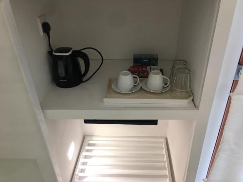 a cupboard with two cups and a coffee maker on a shelf at Saffron Robes Living in Hikkaduwa