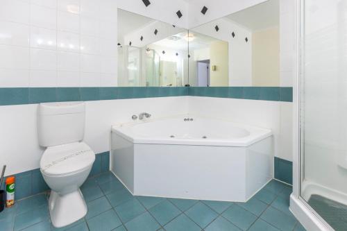 a bathroom with a tub and a toilet and a mirror at ASURE PRINCE motor lodge in Taupo