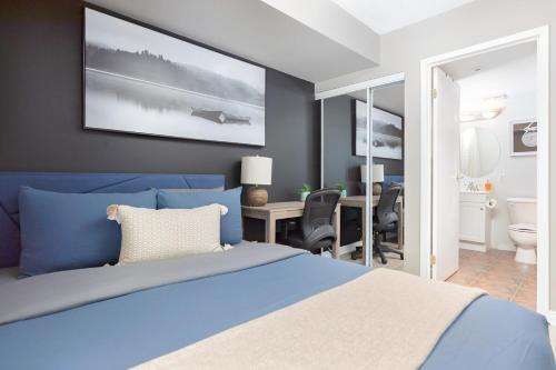 a bedroom with a blue bed and a desk at Lakeside Haven - Cozy Townhome in Liberty Village in Toronto