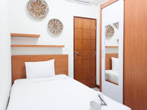 a bedroom with a white bed and a mirror at Spacious and Comfortable 3BR Vida View Makassar Apartment By Travelio in Pampang