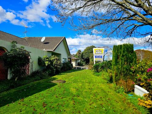 a house with a sign on the side of a yard at Takanini Park Motor Lodge in Auckland