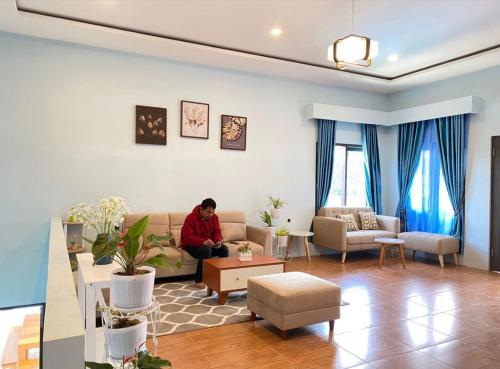 a man sitting on a couch in a living room at Villa meilody 1 - jek space in Paragajen