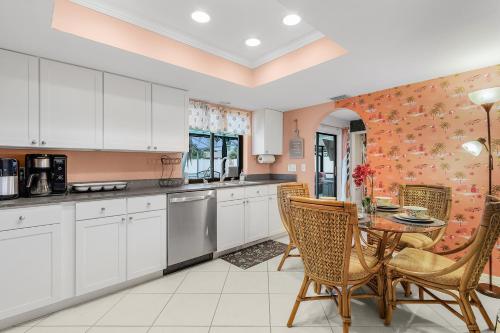 a kitchen with white cabinets and a table and chairs at Green Oasis Retreat in Cape Coral