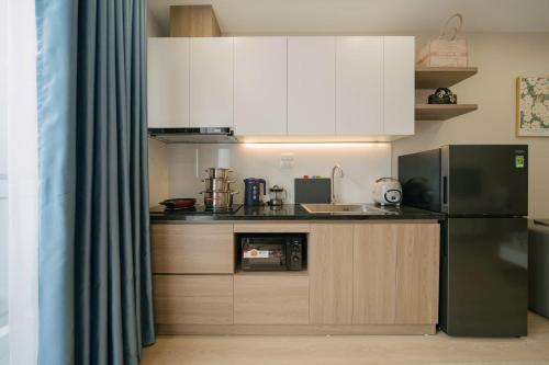 a kitchen with white cabinets and a black refrigerator at Lux Apartment Ngọc Khánh 2 in Hanoi