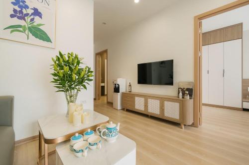 a living room with a tv and a table with vases at Lux Apartment Ngọc Khánh 2 in Hanoi