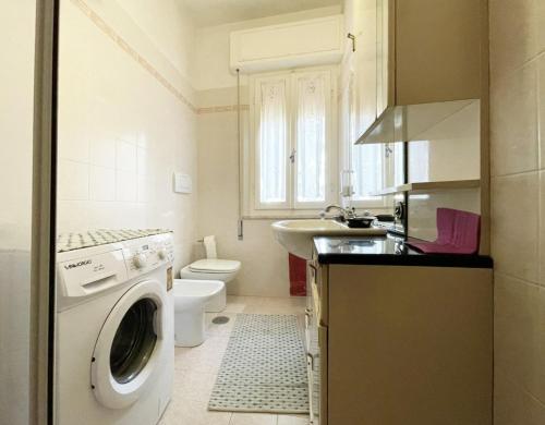 a bathroom with a washer and a sink and a toilet at Gardenia House in Marina di Grosseto