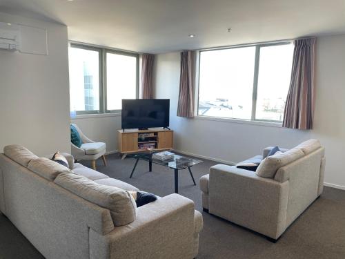 a living room with two couches and a flat screen tv at Apartment in the heart of the city in Christchurch