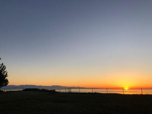 a sunset over the water with a fence at Cliffside Cottage in Oak Harbor
