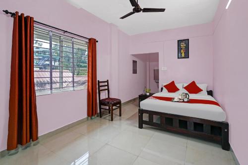 a bedroom with a bed and a window and a chair at Hotel O Valley View Residency in Vagamon
