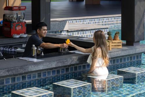 a man and a woman standing at a bar in a swimming pool at Courtyard by Marriott Bangkok Suvarnabhumi Airport in Lat Krabang
