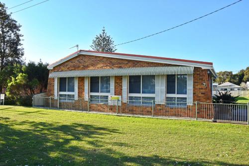 a brick house with a fence in front of a yard at Mountain View Hat Head - Bring your own linen. in Hat Head