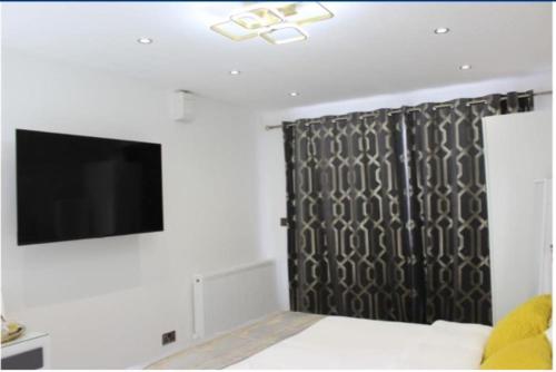 a bedroom with a bed and a tv and a curtain at Mini Cosy Studio Flat Milton Keynes in Milton Keynes