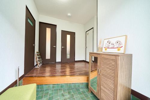 a room with wooden floors and a room with doors at 堀田フォレストハウス in Beppu