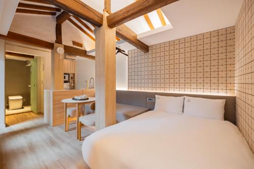 a bedroom with a large white bed and a kitchen at Luxury Hanok Cottage Lunar in Seoul
