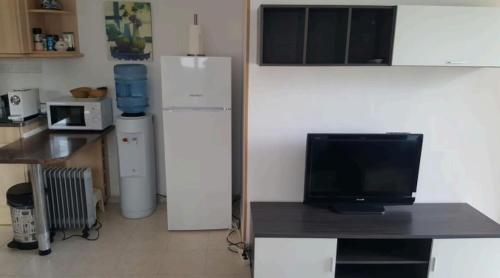 a kitchen with a refrigerator and a table with a television at Pequeño estudio muy lindo a 500 m de la playa in L'Escala