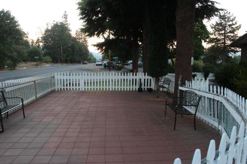 a white fence next to a sidewalk with benches at Cedarwood Inn of Ashland in Ashland