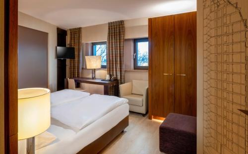 a hotel room with a bed and a chair at Mövenpick Hotel Hamburg City in Hamburg