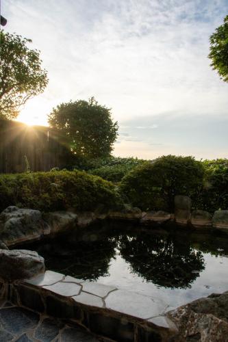 a pond in a garden with the sun setting at Hanare Yado Yosizumi in Ito