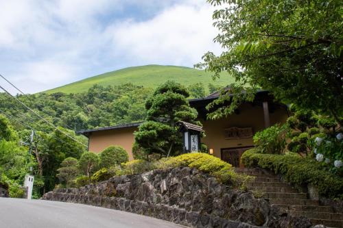 a house with a green hill in the background at Hanare Yado Yosizumi in Ito