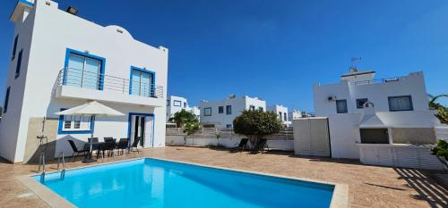 a villa with a swimming pool in front of a building at Villa Amaryllis in Paralimni