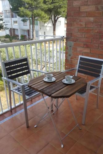 a wooden table and two chairs on a balcony at Pequeño estudio muy lindo a 500 m de la playa in L'Escala