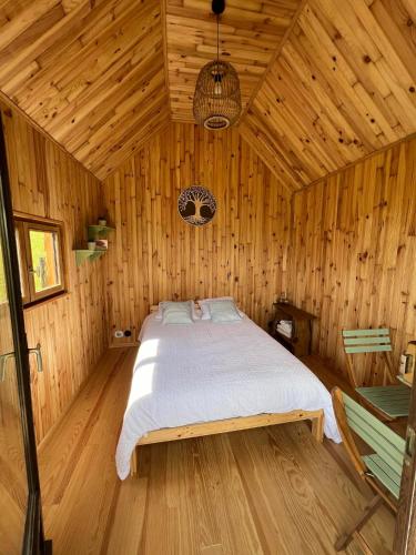 une chambre avec un lit dans une cabane en bois dans l'établissement Les cabanes au revers du noitel, à Oëy