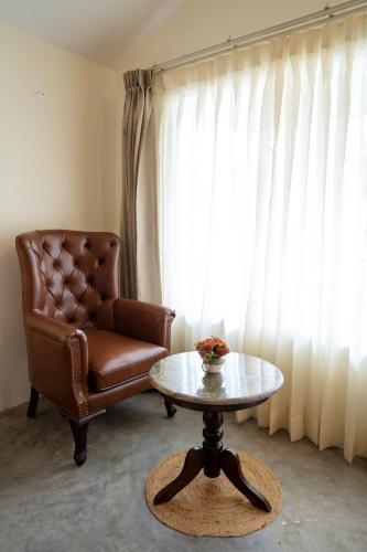 a living room with a chair and a coffee table at Dev Bhoomi Farms & Cottages in Dharamshala
