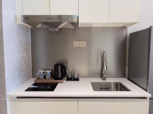 a white kitchen with a sink and a stove at Slow Cloud Residence - Gongbei Port Zhuhai Station in Wan-tzu