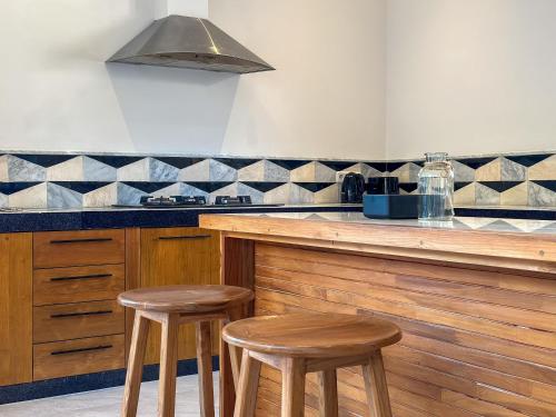 a kitchen with two wooden stools at a counter at Villa Tegal lovina in Buleleng
