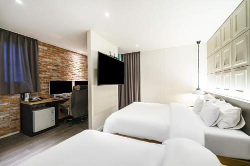 a hotel room with two beds and a desk at Hotel Yaja Pyeongtaek St in Pyeongtaek