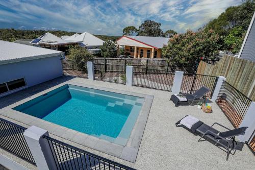 a swimming pool in a yard with chairs and a house at Aquatic Abode in Agnes Water