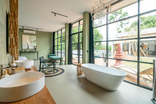 a bathroom with two white tubs in a room with windows at Rouge - Loft Emylia in Ubud