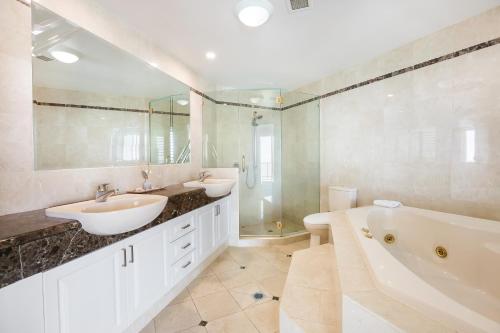 a bathroom with two sinks and a tub and a shower at Sun City Resort managed by Gchs in Gold Coast