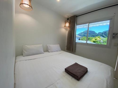 ein weißes Bett in einem Zimmer mit Fenster in der Unterkunft BB Hidden House in Ko Phi Phi