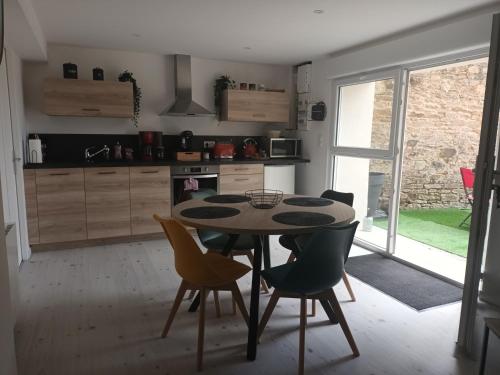 une cuisine avec une table et des chaises dans une pièce dans l'établissement Gite Gambetta magnifique studio cozy, à Ploumagoar
