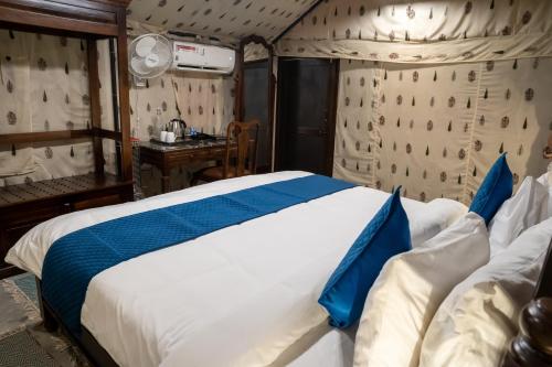 a bedroom with a large bed with blue and white sheets at Dev Bhoomi Farms & Cottages in Dharamshala