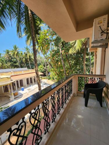 a balcony with a chair and palm trees at The Regal Luxury Boutique Stays in Majorda