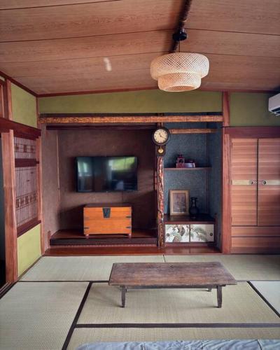 a living room with a tv and a table at 繁華街まで徒歩10分の好立地 観光や食事を楽しむことができます in Amami