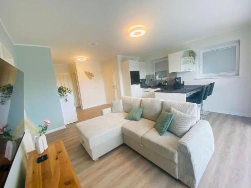 a living room with a white couch and a kitchen at Ferienwohnung in Winterscheid in Ruppichteroth
